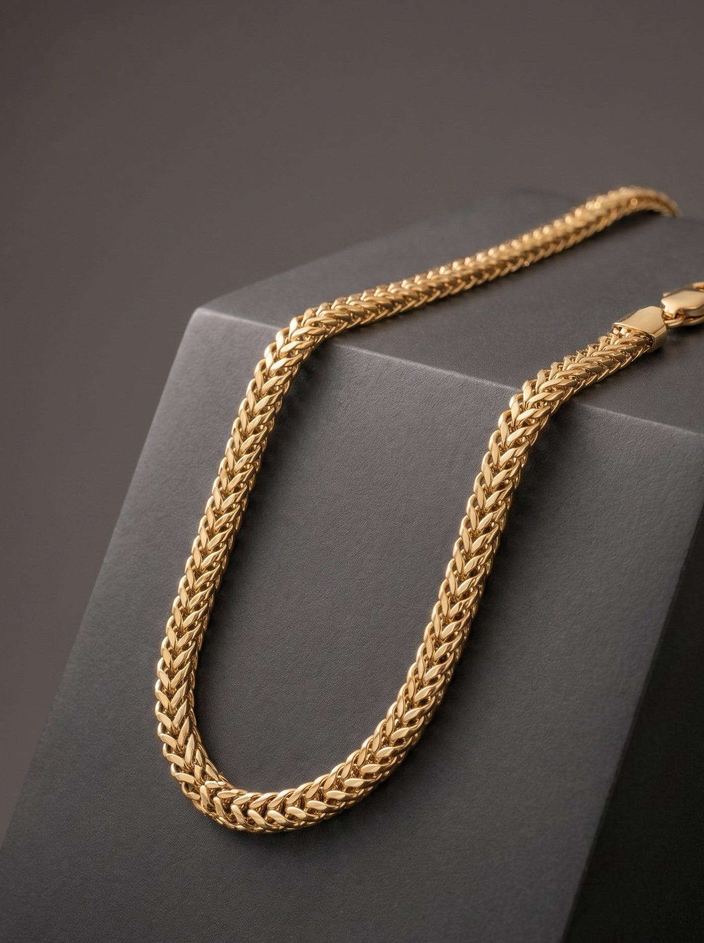 Gold chain necklace on a dark gray surface
