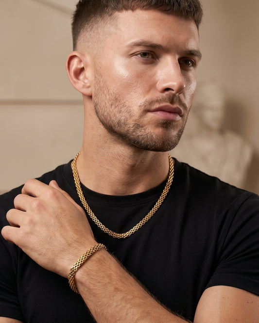 Man wearing a black t-shirt and gold chain in an indoor setting