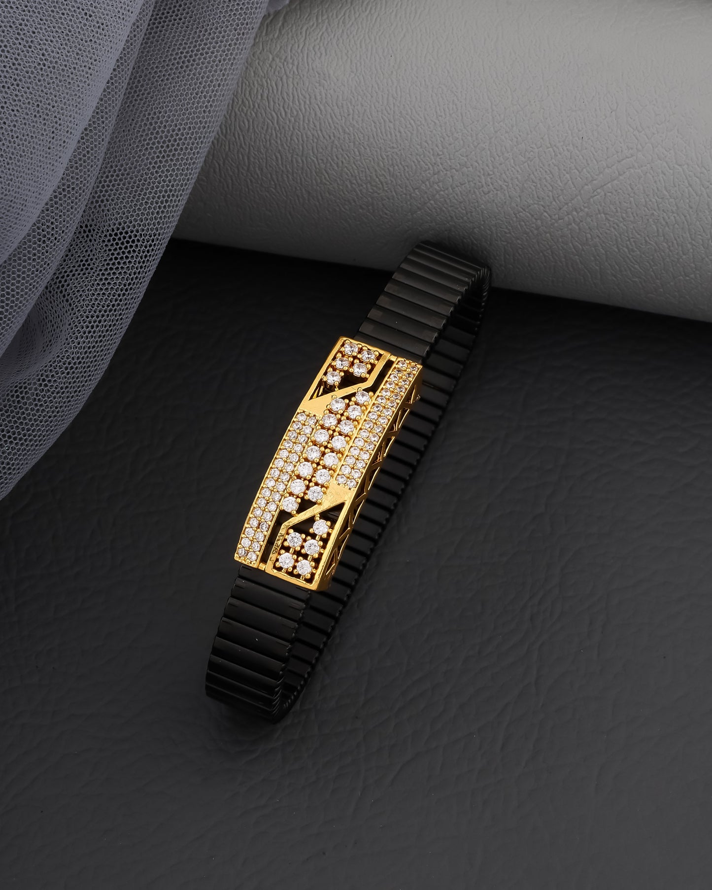 Gold and black bracelet on a dark textured surface