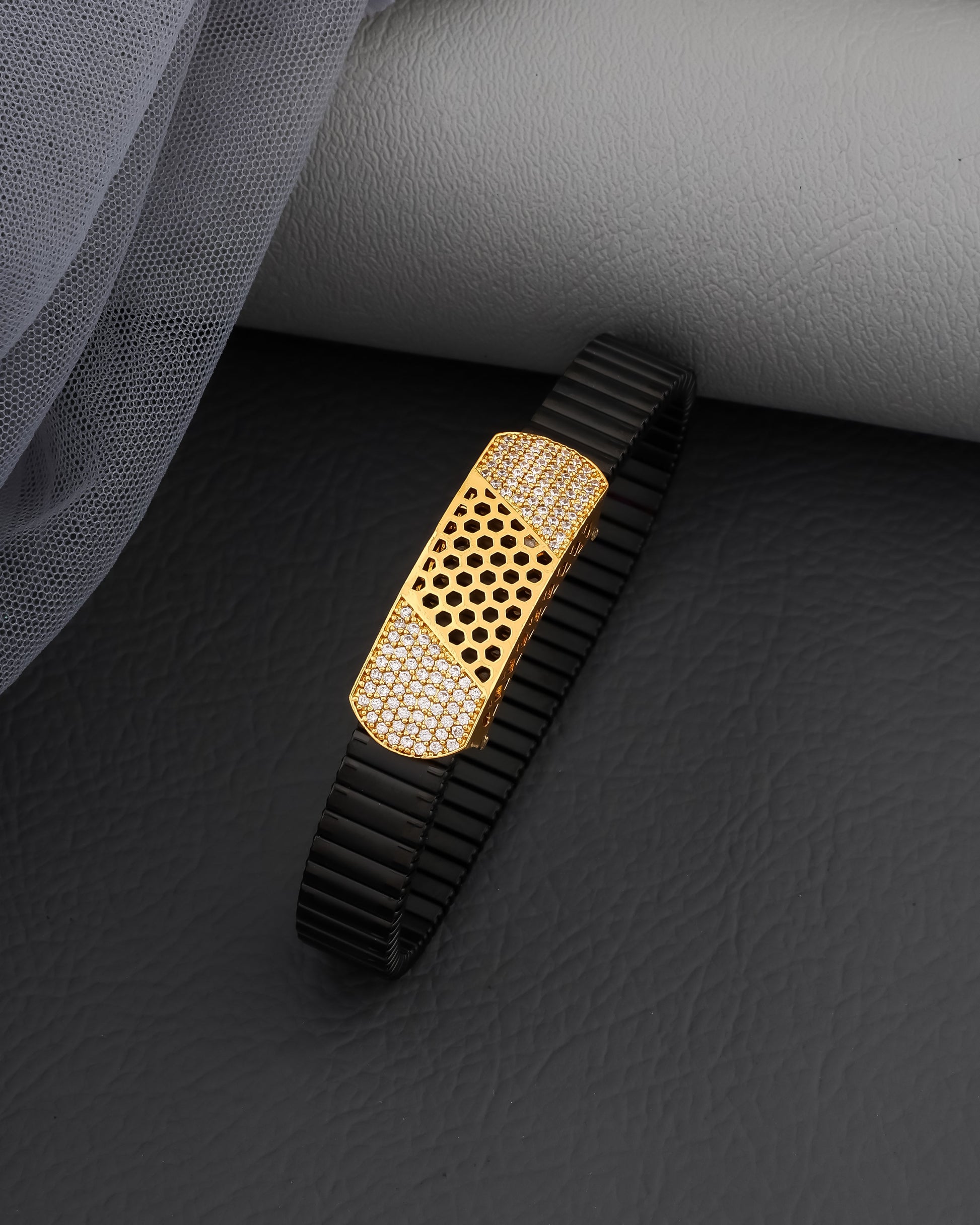 Black and gold watch strap on a dark surface with gray fabric background