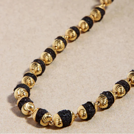 Bracelet with gold and black beads on a beige background