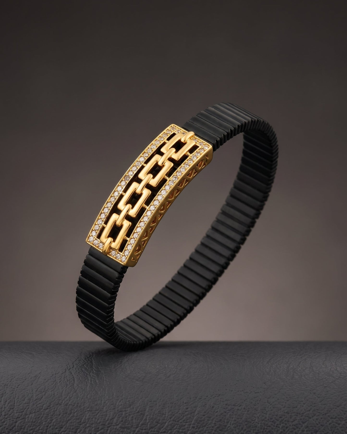 Black rubber bracelet with gold clasp on a dark background