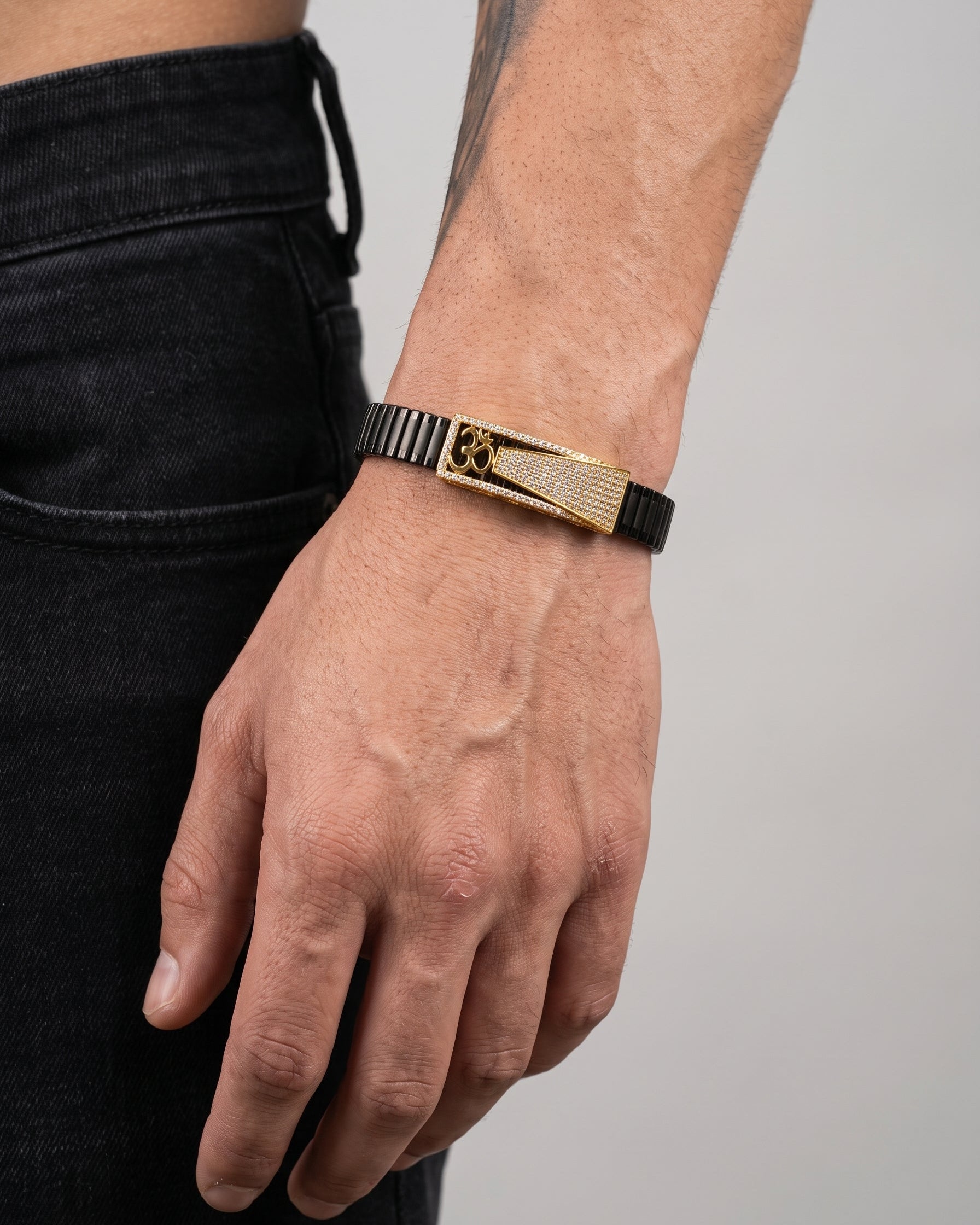 Gold and black bracelet on a wrist with a neutral background