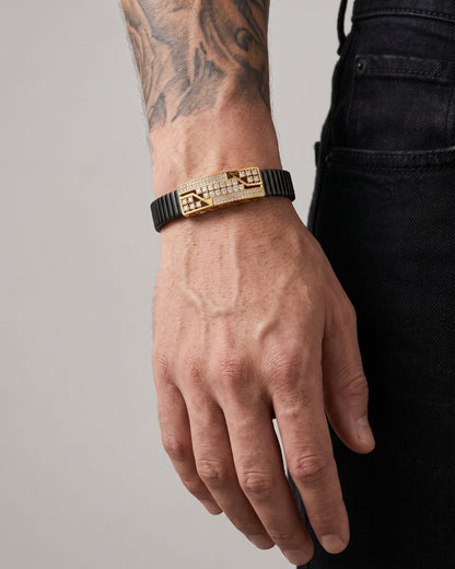 Hand wearing a gold and black bracelet on a neutral background