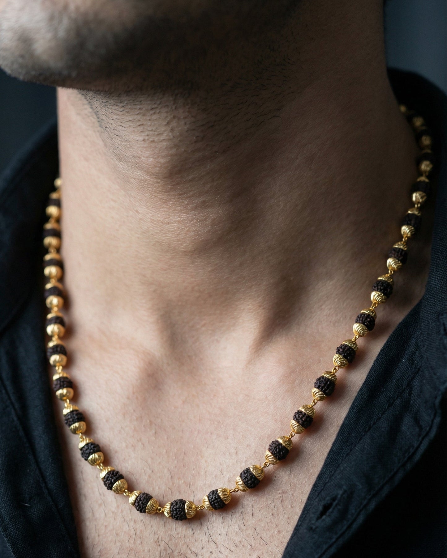 Close-up of a person wearing a black and gold beaded necklace.